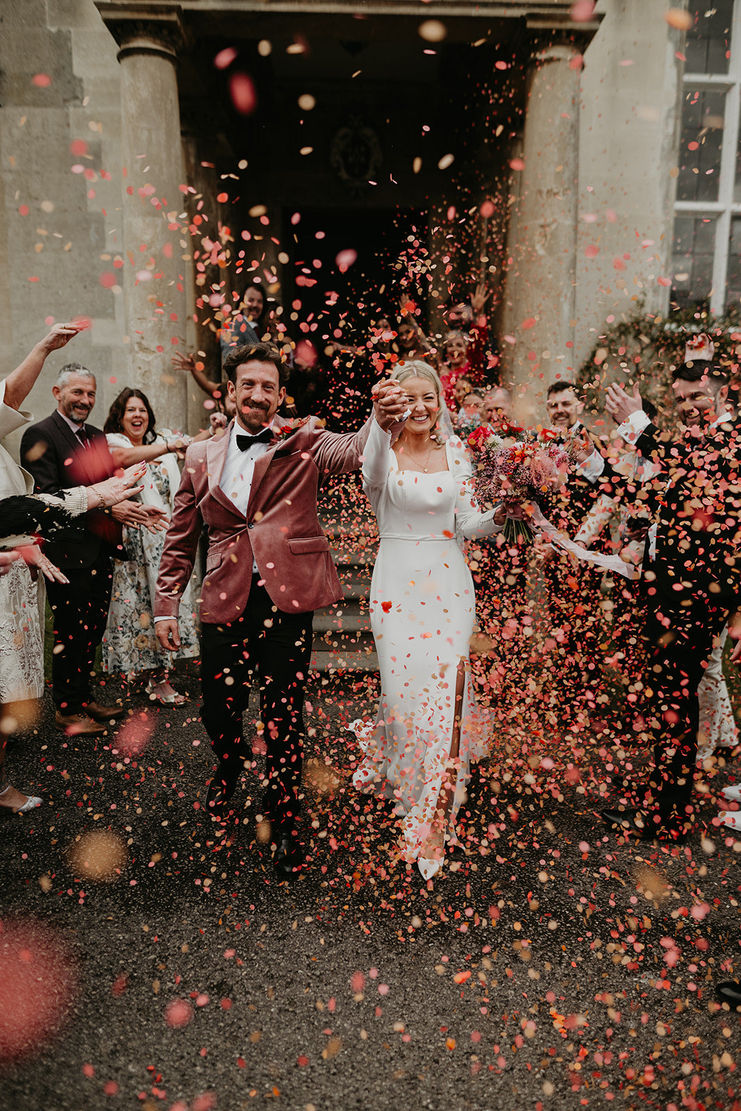 Confetti being thrown over real couple with an autumnal colour palette