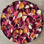 Bright, colourful rose petals displayed in circular plate.