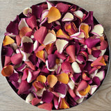 Bright, colourful rose petals displayed in circular plate.